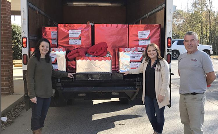 Franklin County Schools Social Worker Nikki Croy accepts a donation of coats and hoodies for Franklin County Schools from Harbin Lumber Company.